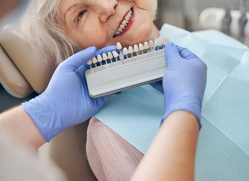 Senyora gran provant el color dels implants dentals a un dentista